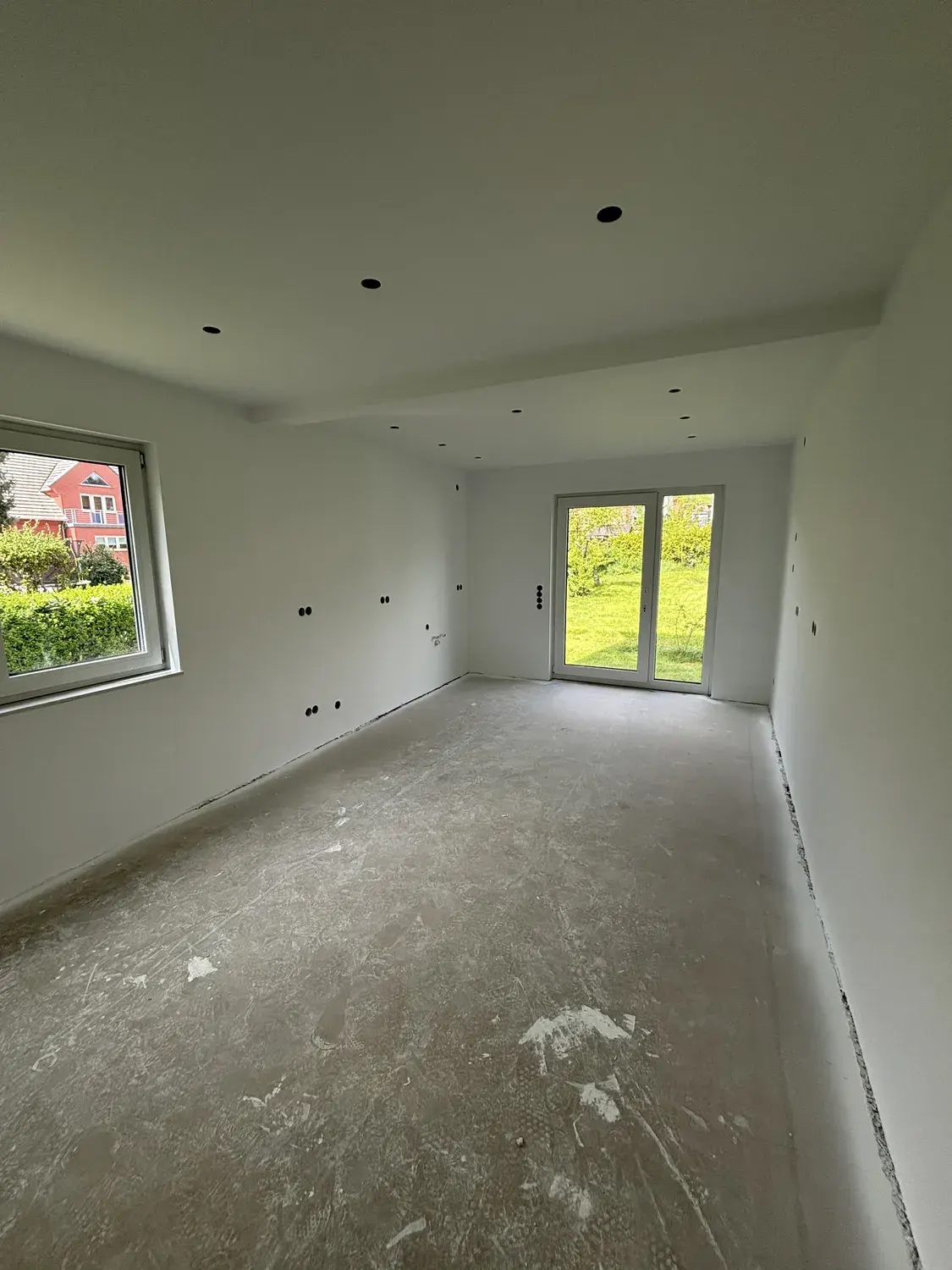 Derselbe Raum nach dem Ausbau mit weiß gestrichenen Wänden, neuer Spotdecke und Glastür zum Hof