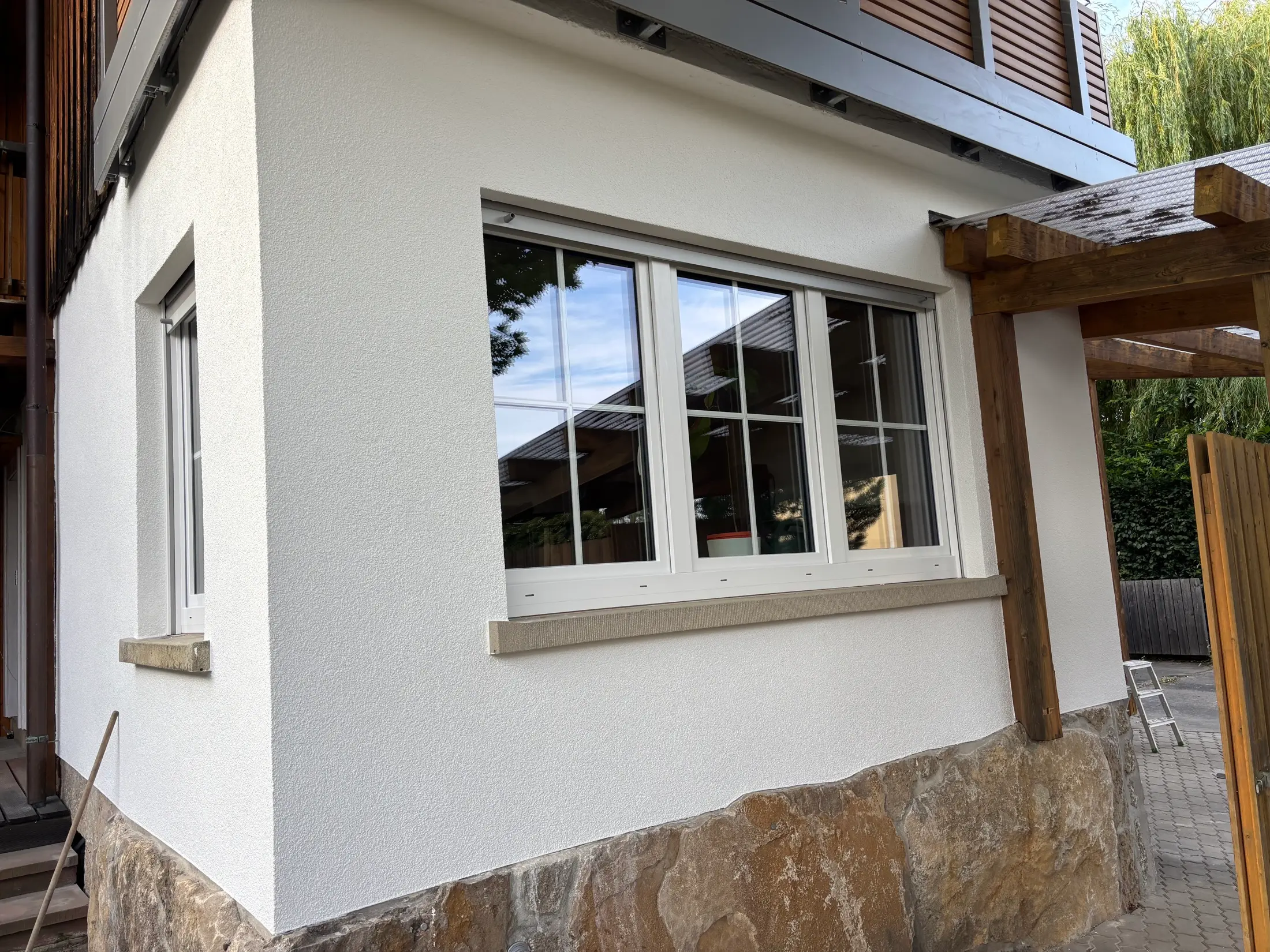 Detailansicht einer fertig sanierten weißen Fassade mit neuem Sprossenfenster
