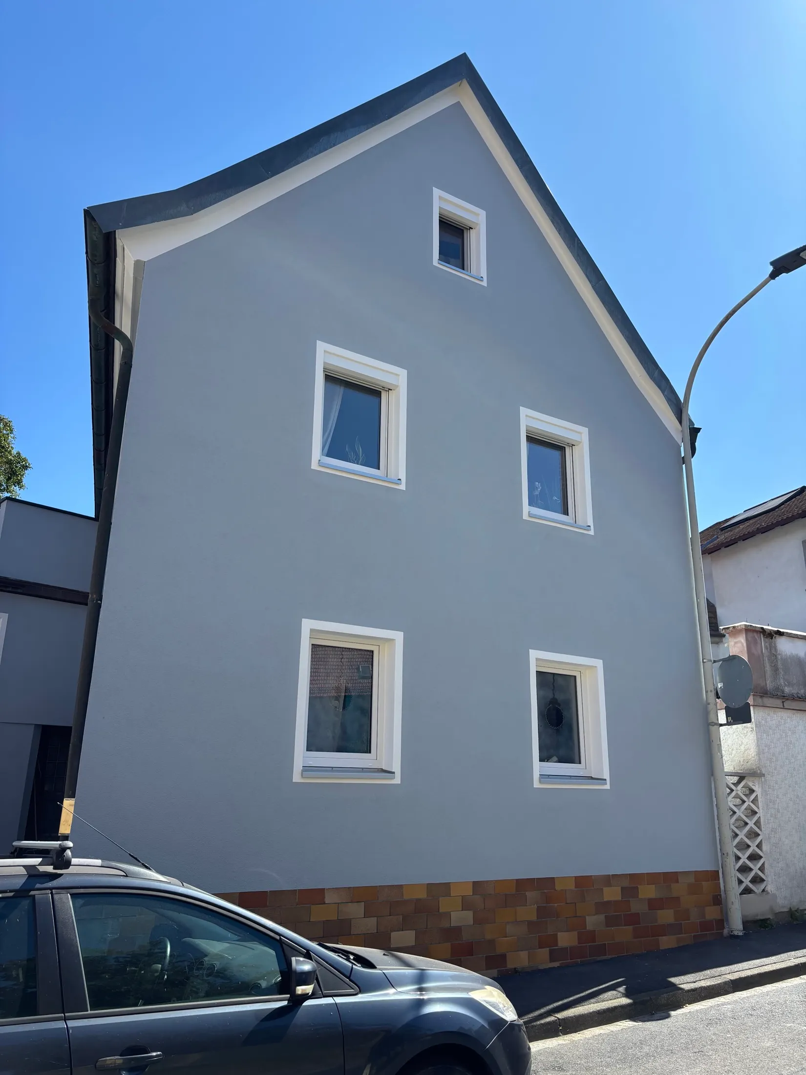 Blaugrau gestrichene Giebelfassade mit weiß abgesetzten Fenstern