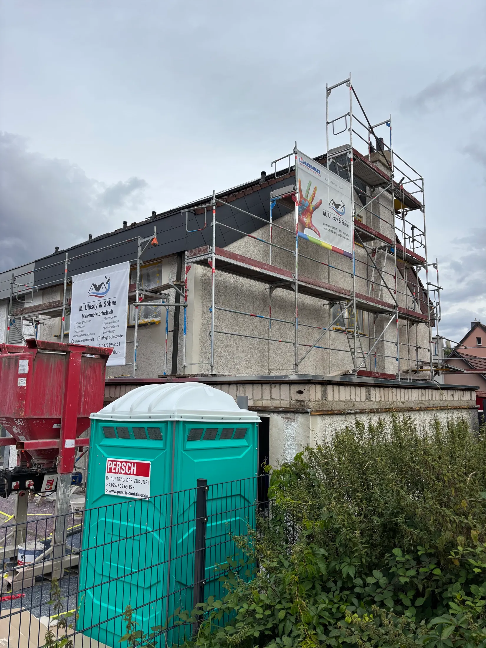 Eingerüstetes Wohnhaus während der Fassadenarbeiten mit Werbebannern von M. Ulusoy & Söhne