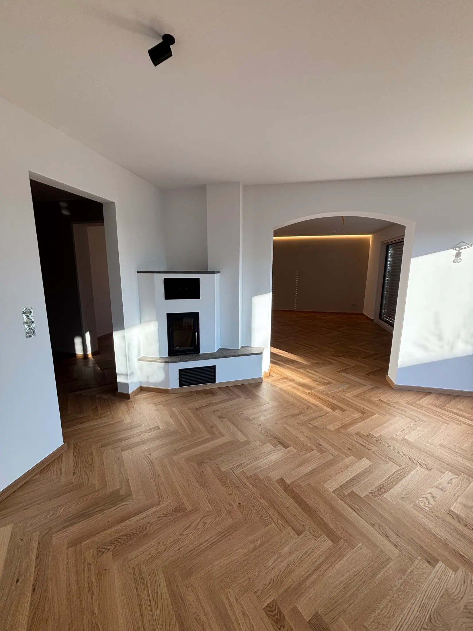 Renoviertes Altbau-Wohnzimmer mit Rundbogen, Kamin und frisch gestrichenen Wänden