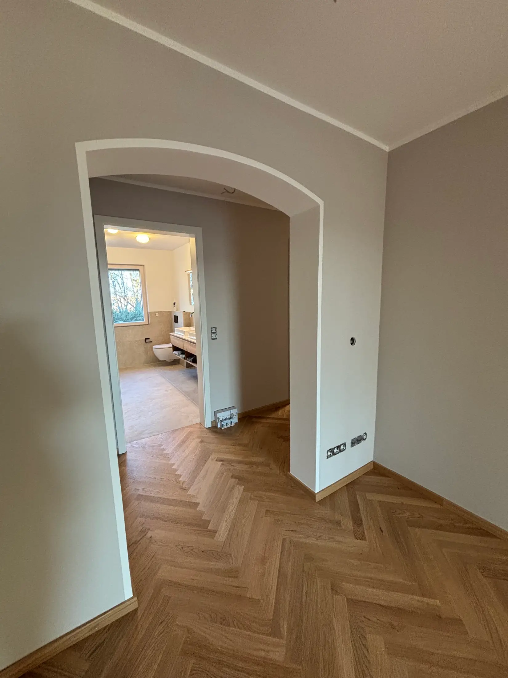Flur mit Rundbogen und greige gestrichenen Wänden nach Komplettrenovierung