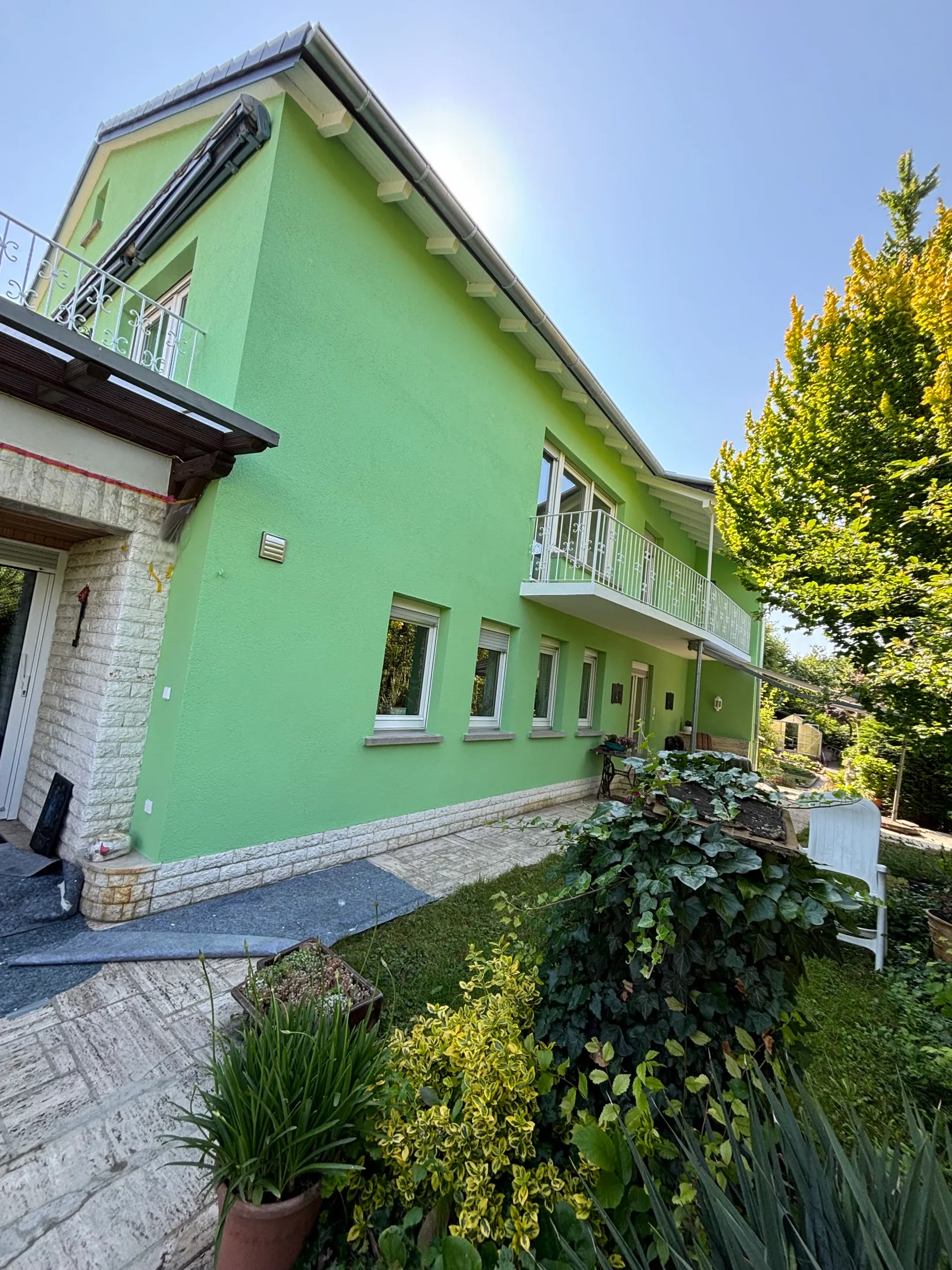 Frisch grün gestrichenes zweigeschossiges Wohnhaus mit Natursteinsockel