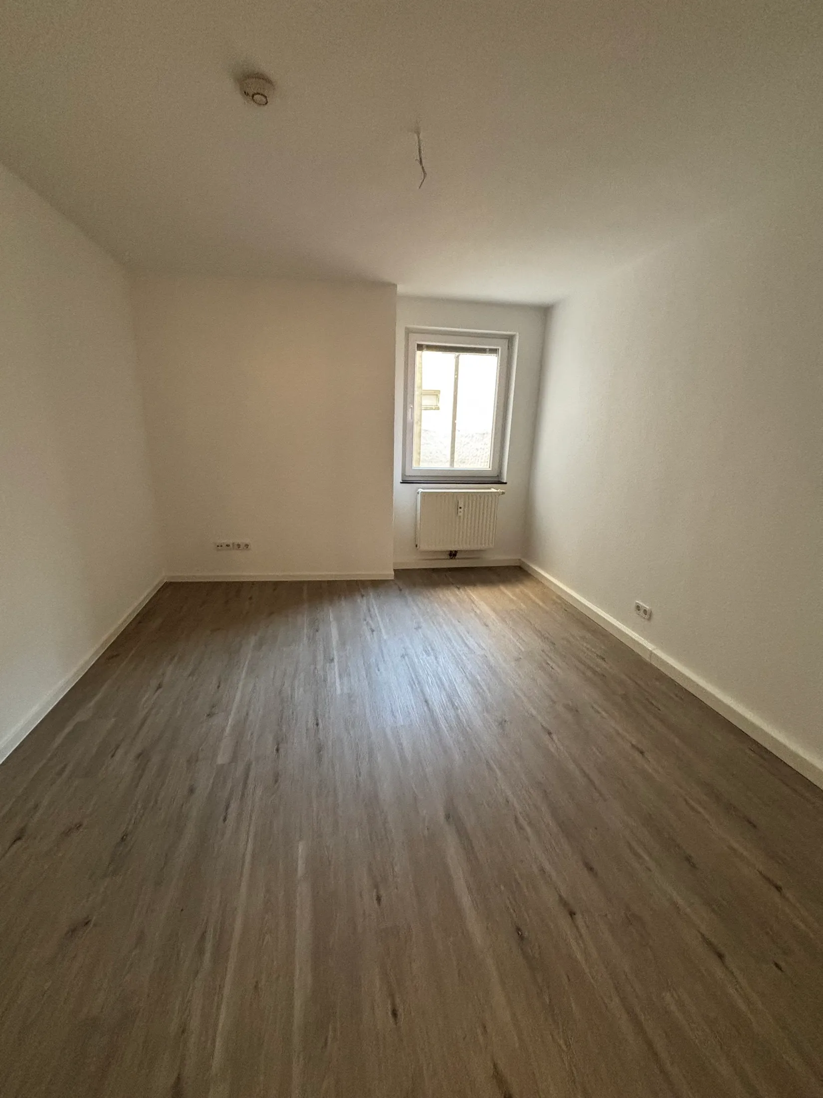 Renoviertes Zimmer mit neuem grauem Vinylboden und lackierter Tür