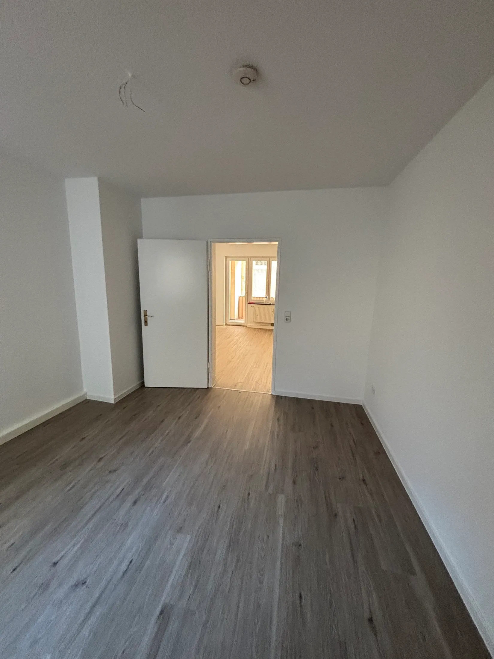 Fertig renoviertes Zimmer mit Blick durch die Tür in den Nebenraum