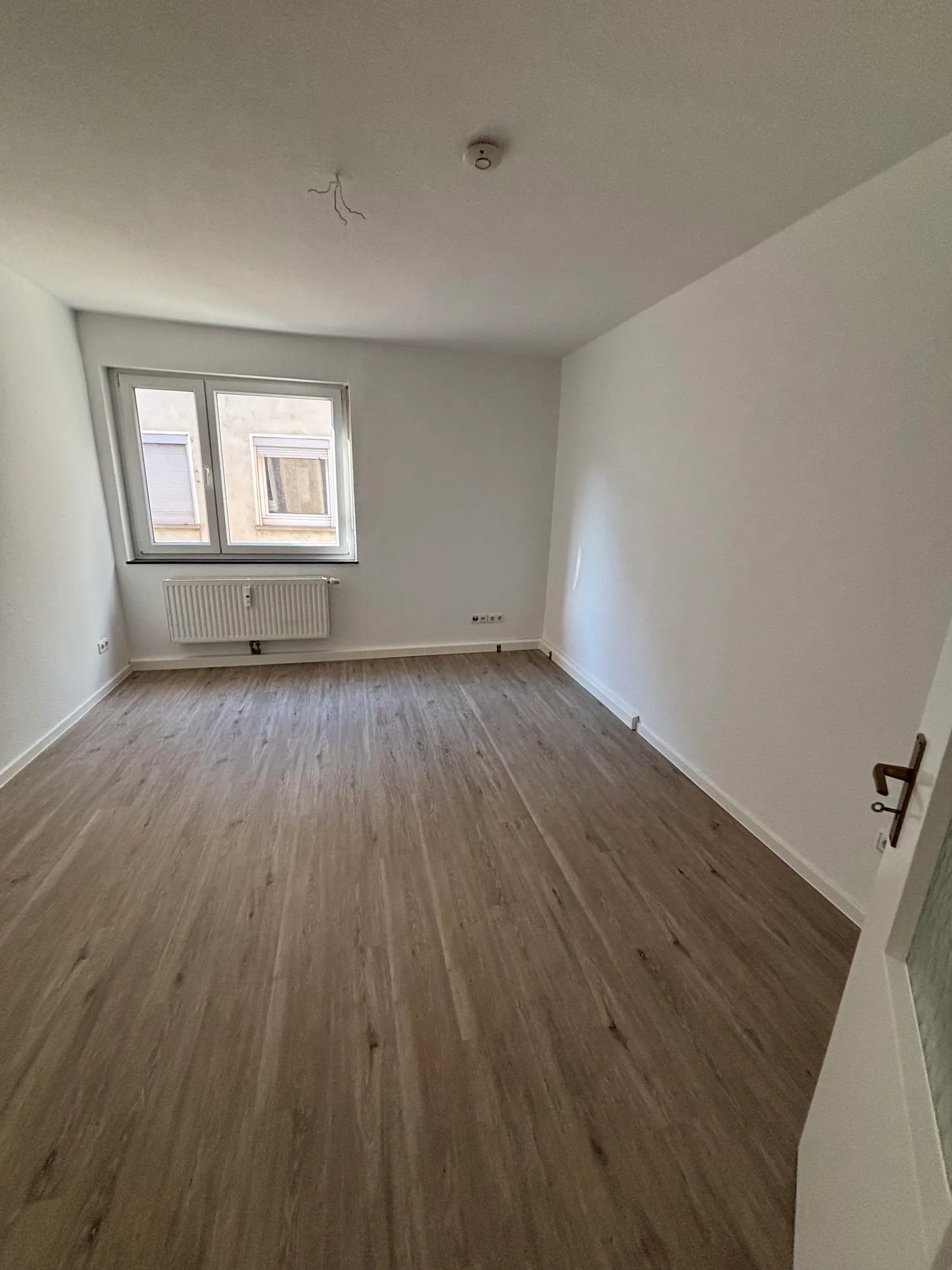 Helles renoviertes Zimmer mit neuem Vinylboden in Holzoptik und weißen Wänden
