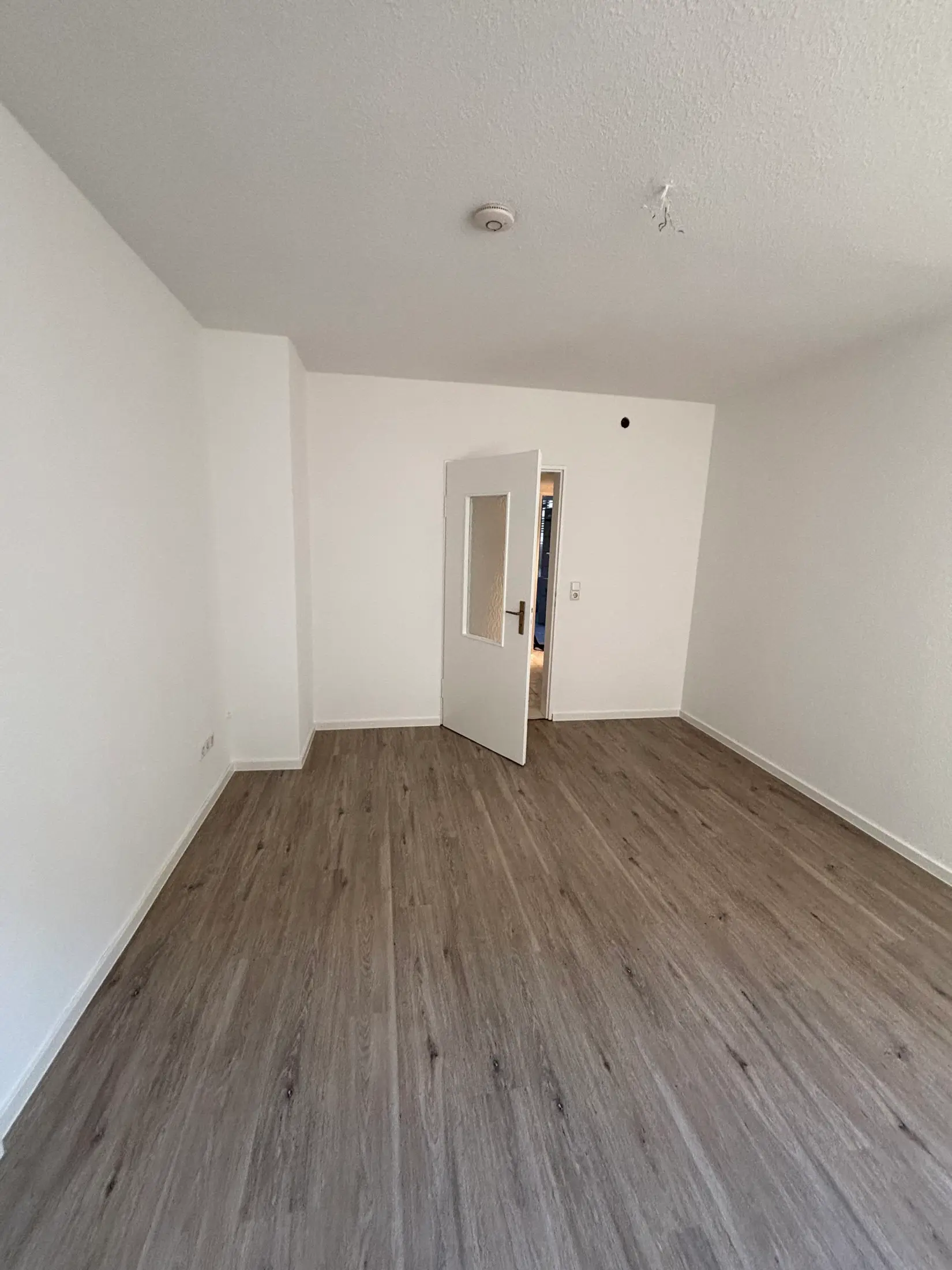 Saniertes Zimmer mit neuem Vinylboden und weiß gestrichenen Wänden in Würzburg