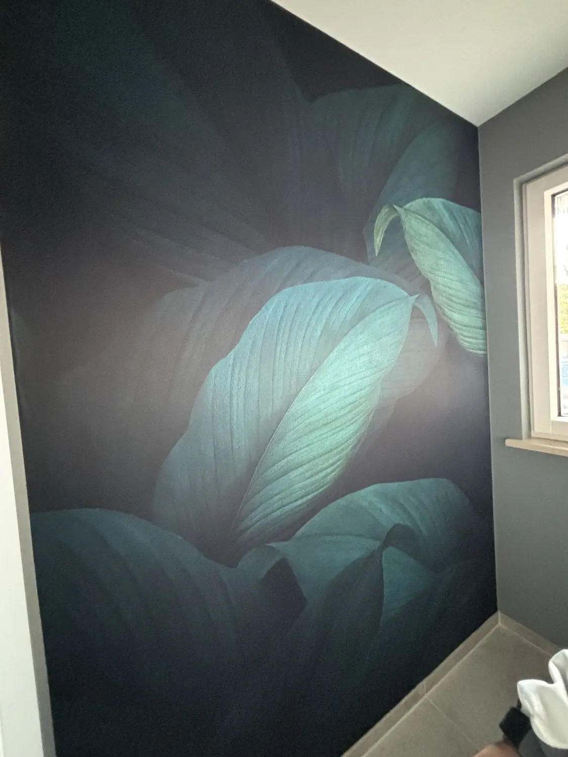 Fertig tapezierte Wand mit großformatiger tropischer Blätter-Fototapete in Dunkelgrün