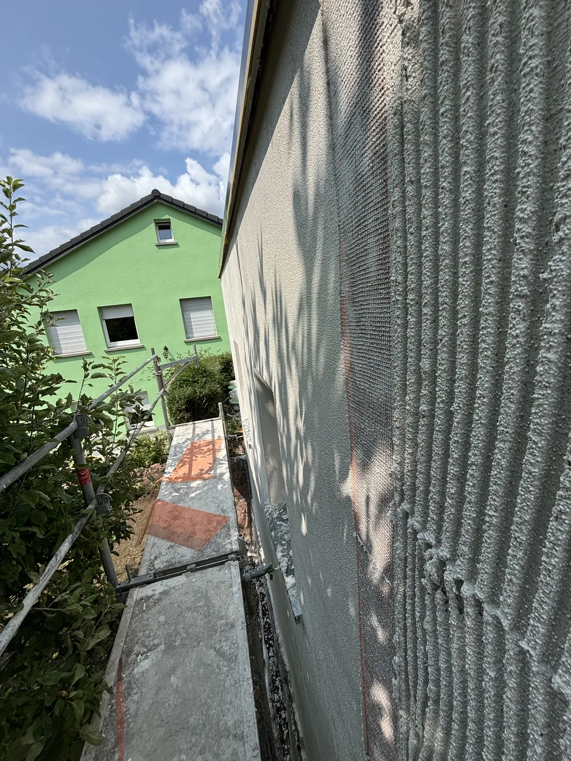 Frischer Armierungsputz mit Gewebe an einer Außenwand während der Putzarbeiten